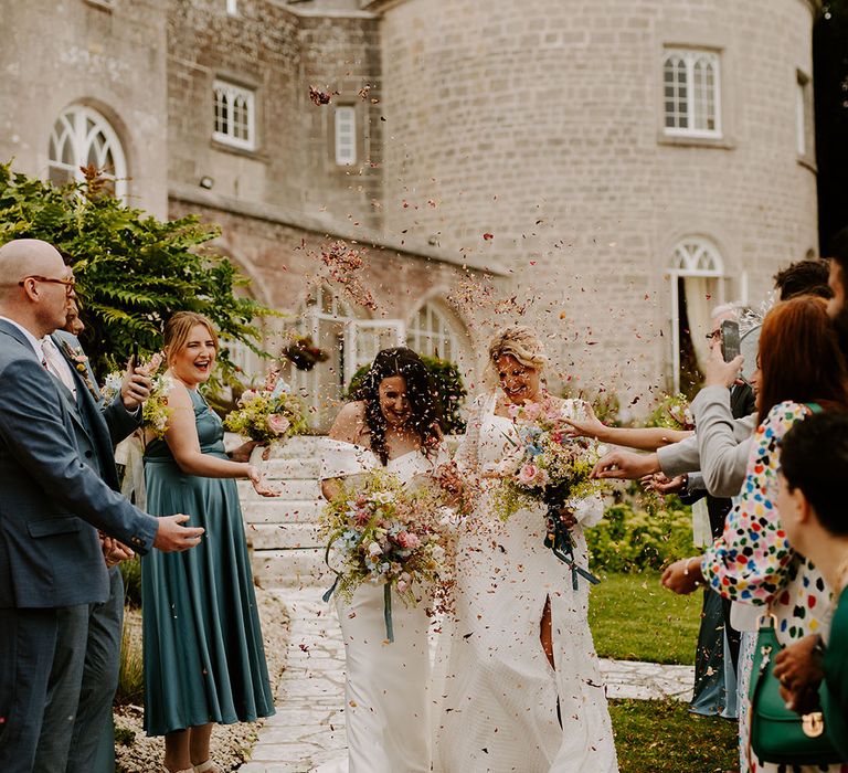 Confetti exit with dried petals for two brides at castle wedding venue in Dorset 