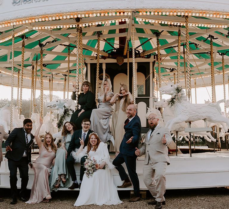 Carousel at fairground wedding featuring the whole wedding party in group wedding photo 