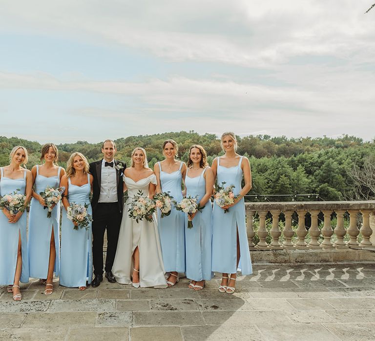 Bridal party wearing powder blue bridesmaid dresses posing with the bride and groom at destination wedding 