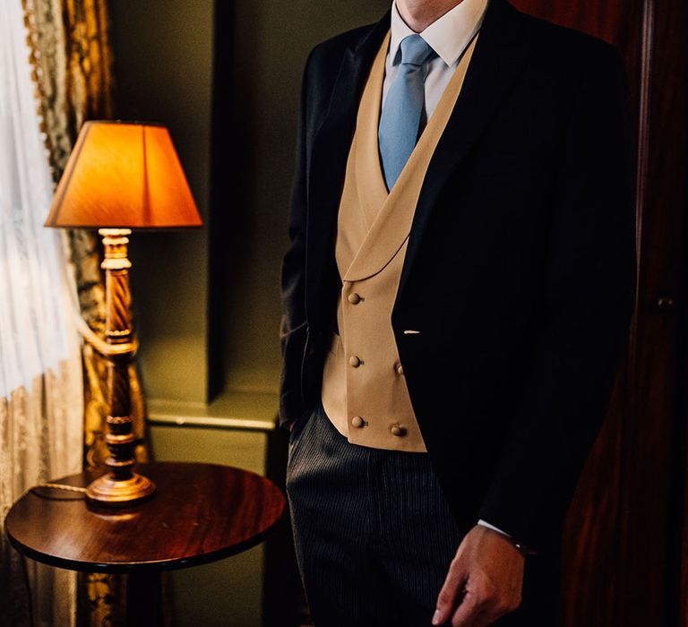 Groom wearing three piece morning with blue tie 