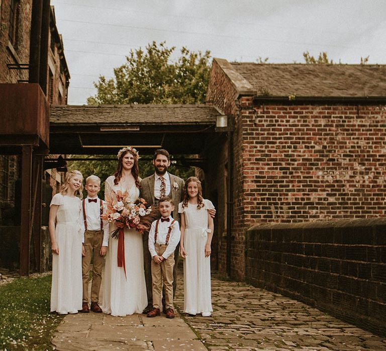 Bride and groom posing with the flower girls and page boys at their wedding 