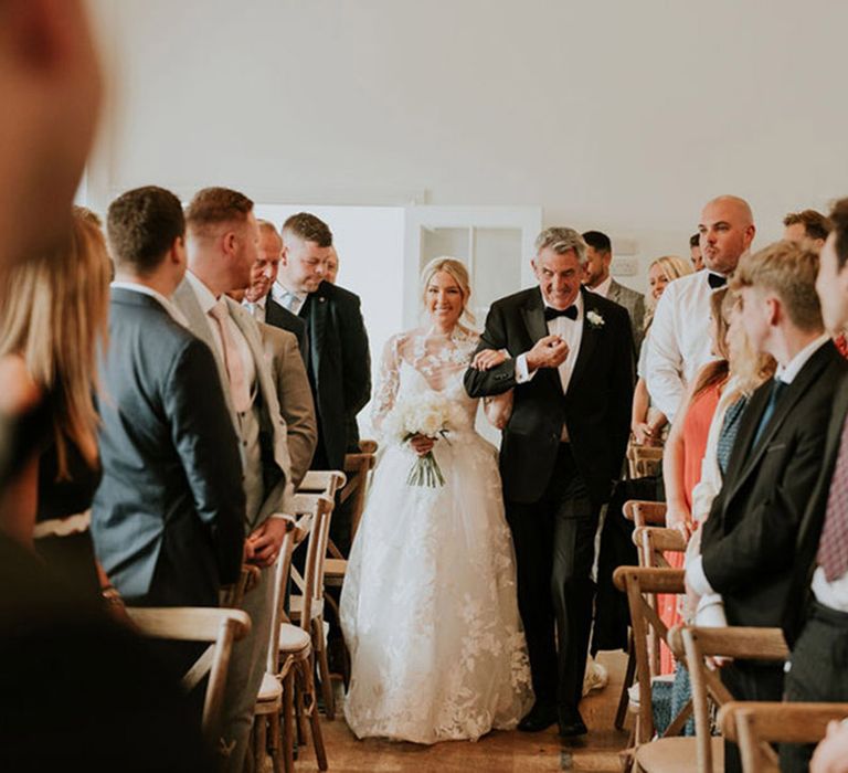 Father of the bride and bride walk down the aisle together 