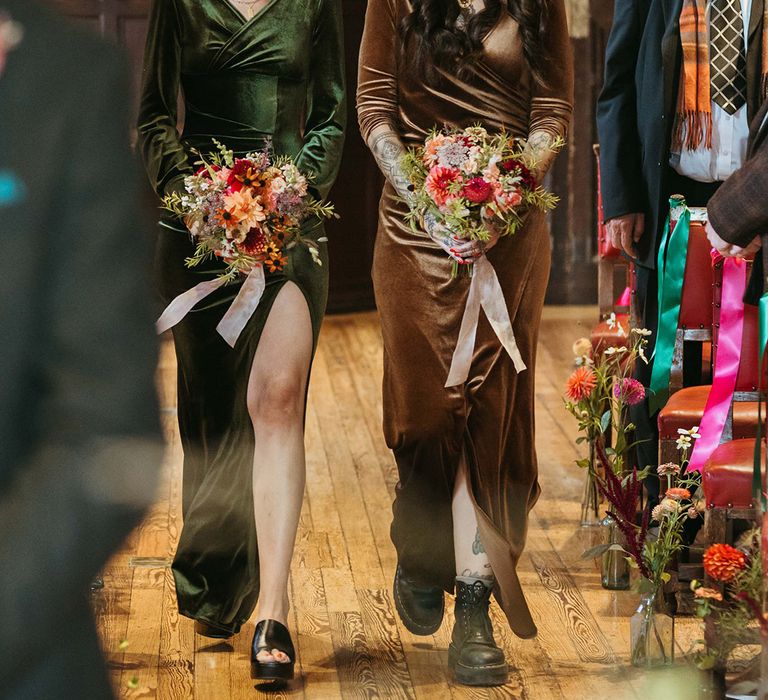 Bridesmaids in autumnal velvet bridesmaid dresses walking down the aisle 