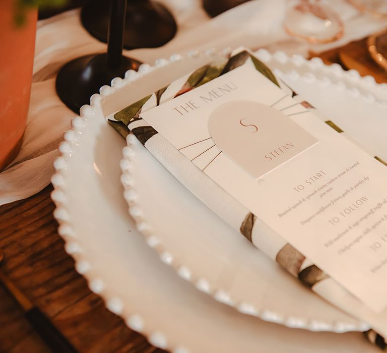 Leaf pattern napkin with classic wedding menu stationery on white plate 