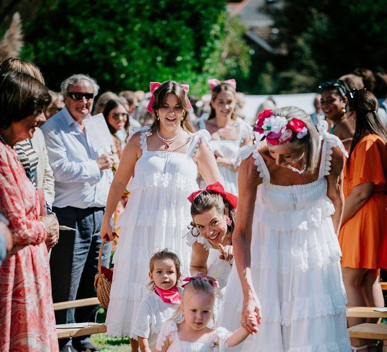 Bridesmaids and flower girls wearing white ruffle layered bridesmaid dresses for coastal wedding 