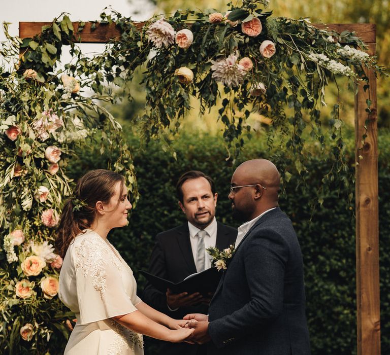 Bride and groom holding hands during english garden wedding 