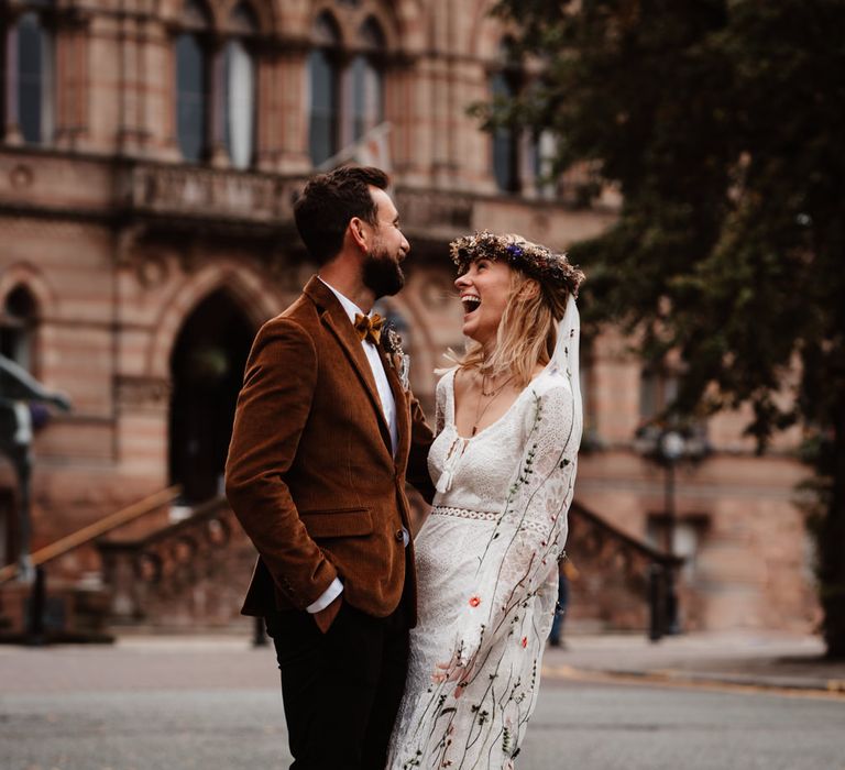 Bride and groom laughing at micro wedding with bride in a embroidered wedding veil