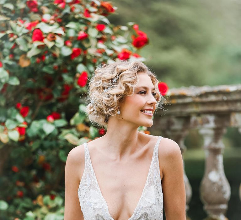 Bride in a plunging V neckline wedding dress with a pinned updo wearing a hair vine and dangling earrings | Charlotte Wise Photography