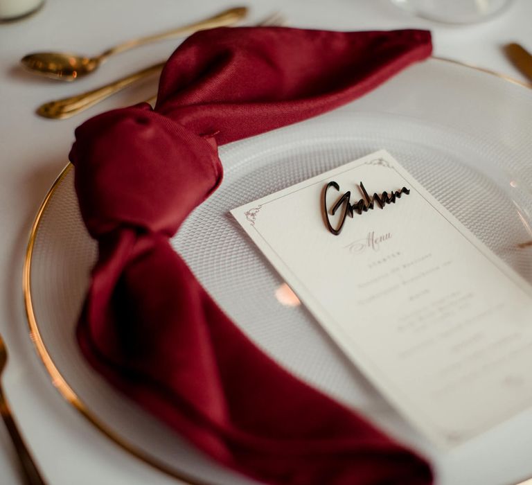 Wedding menu placed on glass plate with a red bow and gold cutlery for autumnal wedding in Manchester 