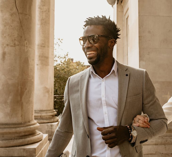 A Black groom holds a white brides hand as they walk through the city for a wedding photo shoot.