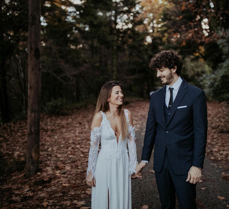 The bride and groom walking through the woodland together