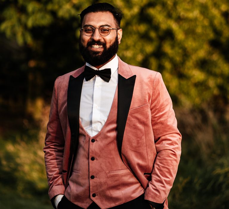 Groom wears pink suit with black bow tie 