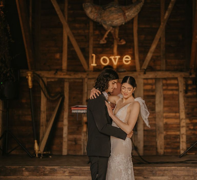 Bride and groom dancing in the barn at Preston Court with neon LOVE sign on the wall 