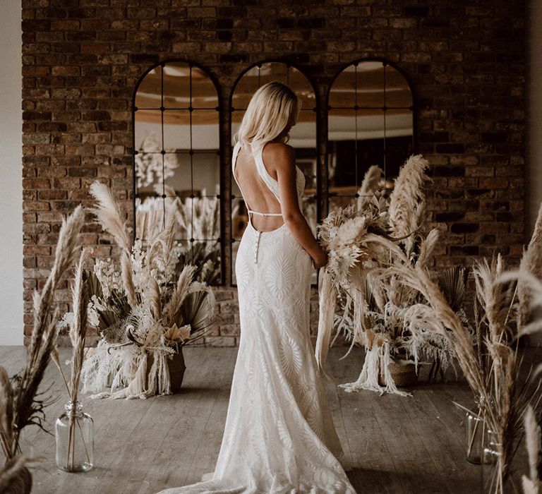 Bride in a patterned wedding dress with cut out back detail surrounded by dried flowers arrangements at Pyrors Hayes wedding venue 