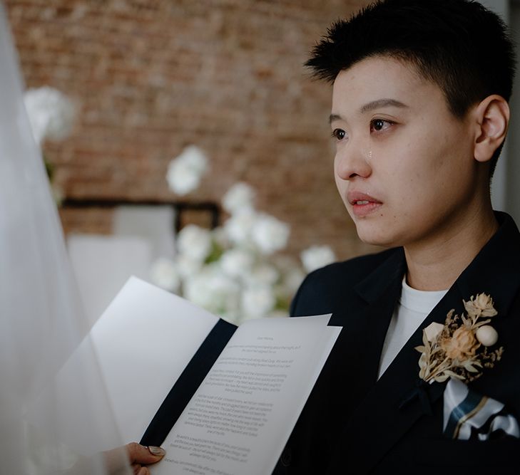 Emotional Asian Lesbian wedding ceremony with bride in navy jacket crying during the vows 