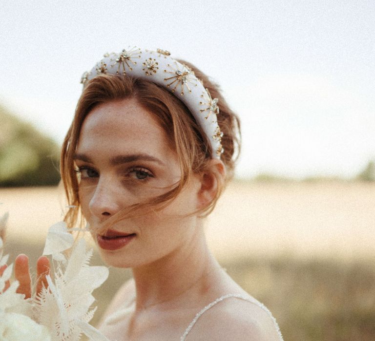 Bride wearing a white and gold beaded headband with all white flower bouquet