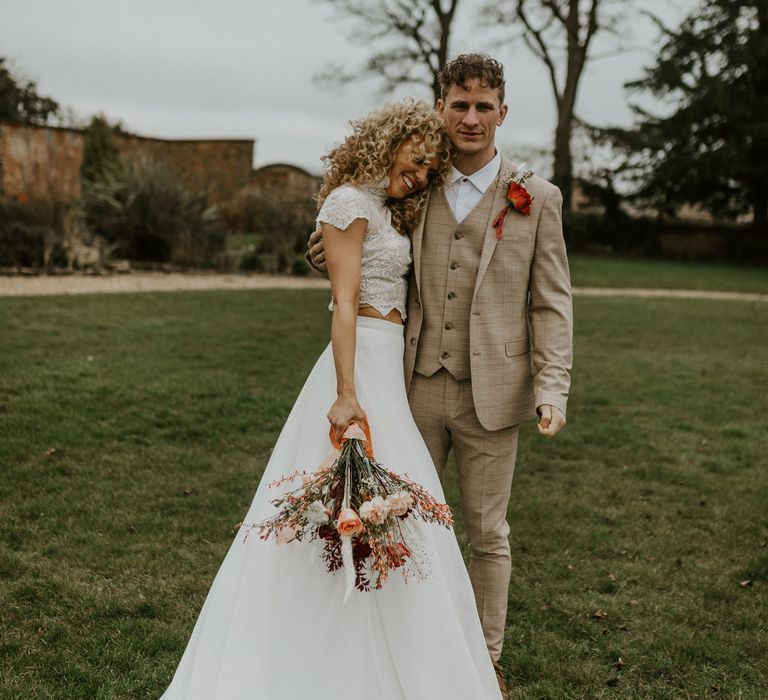 Bride and groom hugging un the grounds at Hornington Manor, both with curly wedding hair