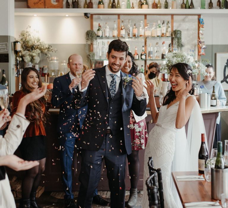 Bride and groom covering in confetti for their entrance at a Hackney pub