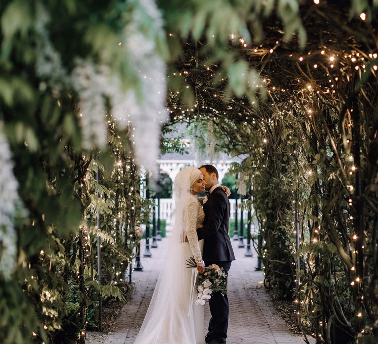 Bride and groom under a fairy lit nature walk way