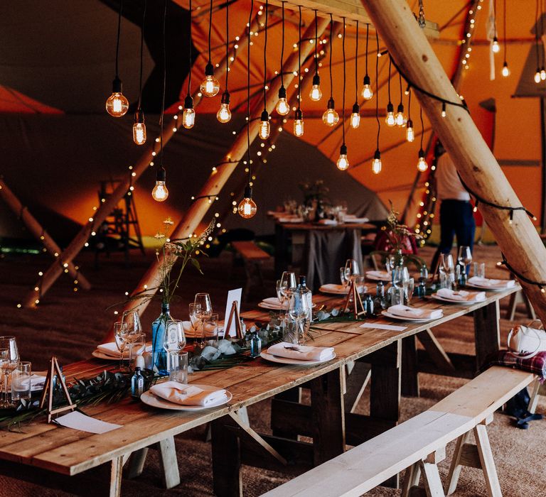 Festival style tipi complete with hanging lights, macrame shades and gin vases 