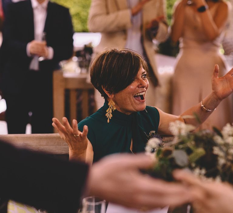 Stylish wedding guest in a teal dress with short hair and gold dangly earrings 