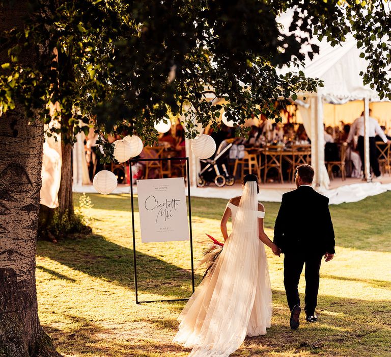 Bride and groom make their way to the marquee wedding with monochrome sign