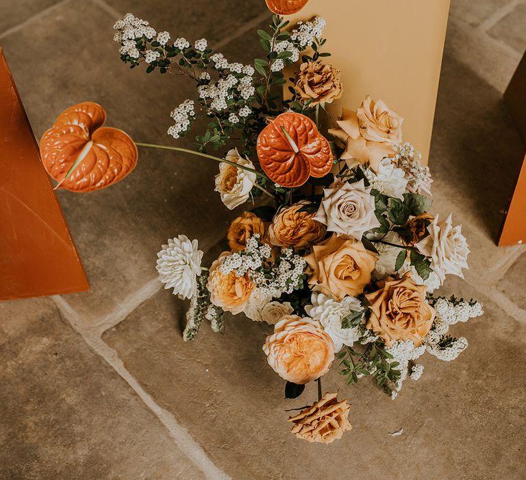 Orange and peach wedding flower arrangement with roses and anthuriums 