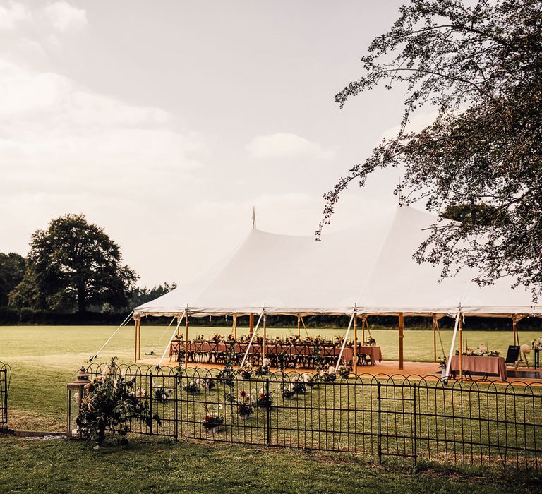 Garden marquee wedding reception with white open sided tent, long dusky pink tables, florals and candles for Cornish wedding