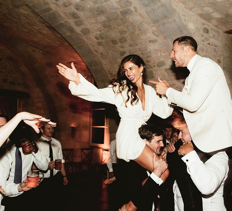 Bride & groom dance on the shoulders of wedding guests on their wedding day