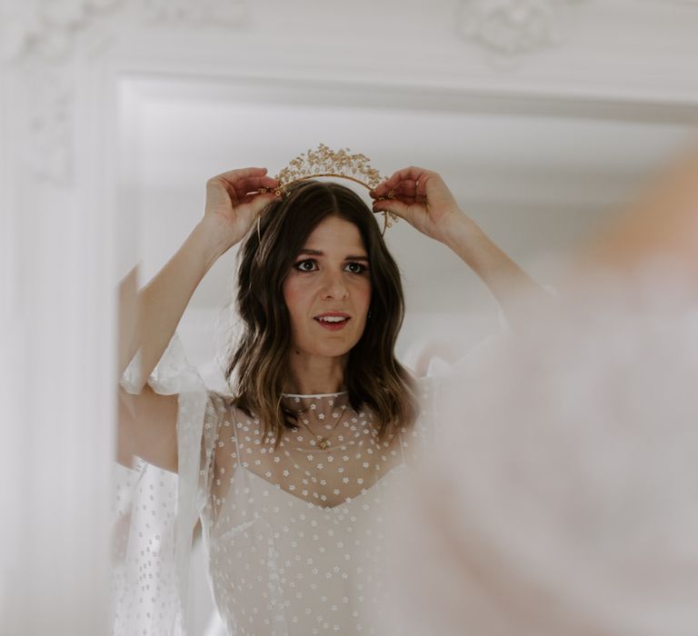 Bride places crown in her hair on her wedding day