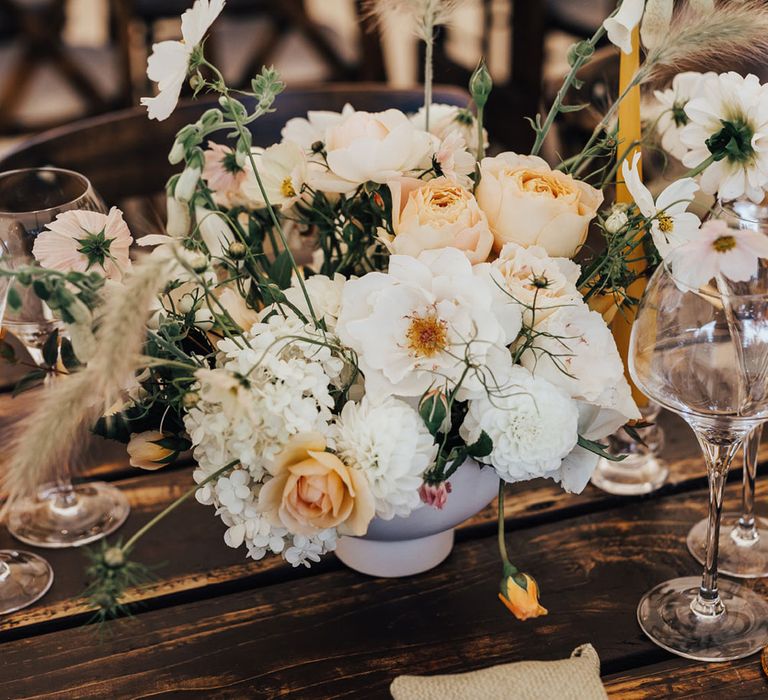 White, peach and green florals at wooden table for Sperry Tent wedding reception