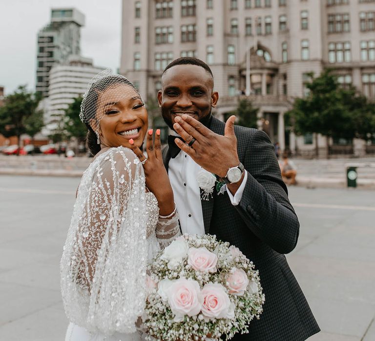 Bride & groom flash their hands with engagement rings and wedding bands on their wedding day