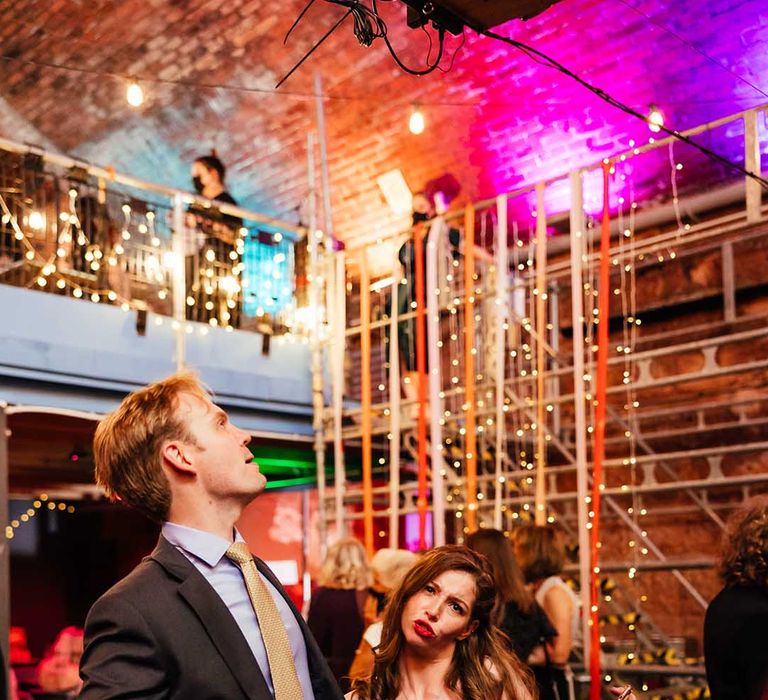 Wedding guests dance in front of colourful lights