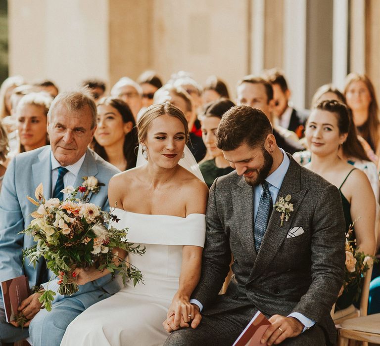 Bride looks at groom on wedding day and smiles during ceremony