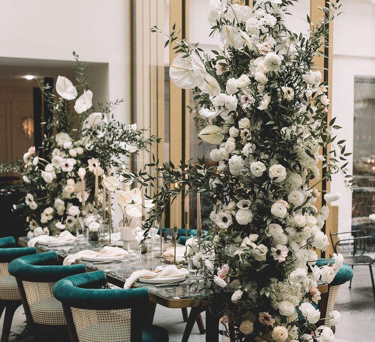 Intimate wedding reception with tall vertical flower arrangement including anthuriums, ranunculus and anemones 