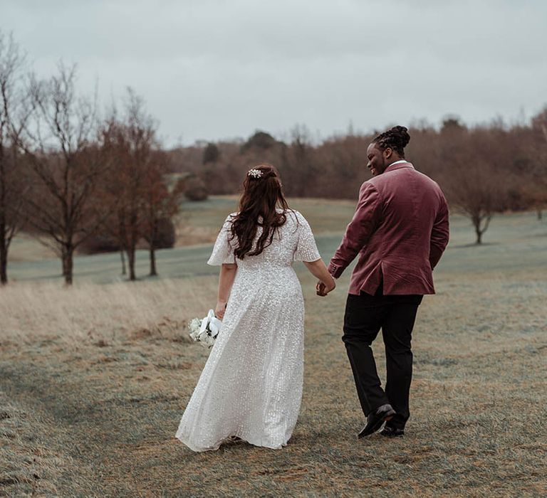 Bride & groom walk across fields on their wedding day