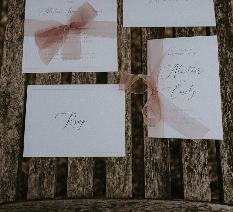 DIY wedding stationery with cursive calligraphy and pink bows and borders