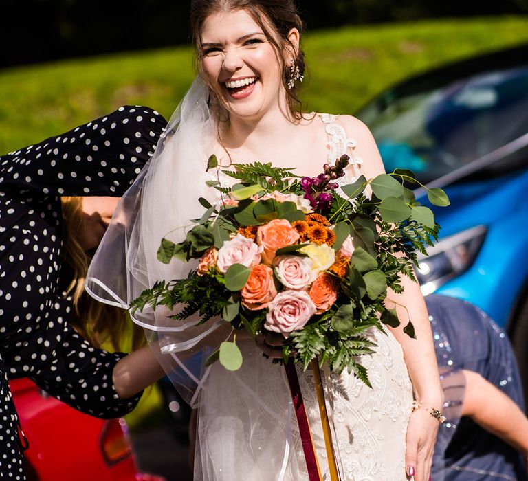 Bride in lace mermaid wedding dress with colourful wedding bouquet, pink wedding nails and leaf jewellery