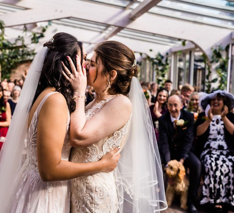 Brides share their first kiss as a married couple as wedding guests applaud