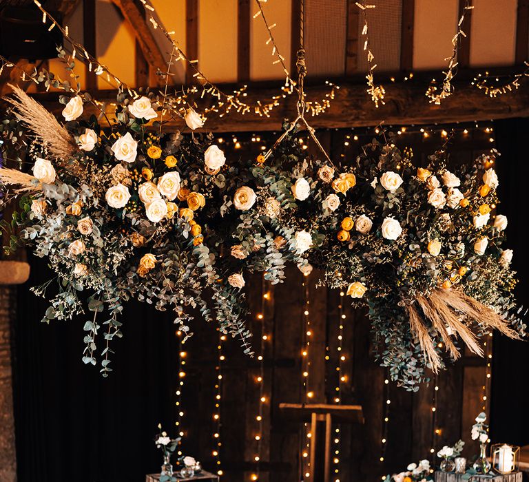 Wedding altar style with rustic wooden crates, gold candle lanterns with white pillar candles and a large orange and white flower cloud 