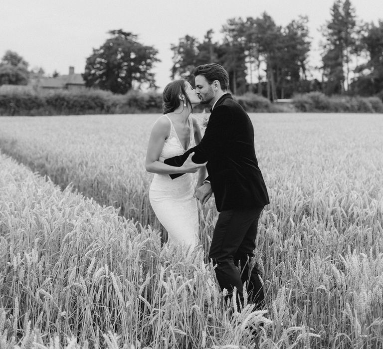 Bride and groom share a kiss in a field of wheat 