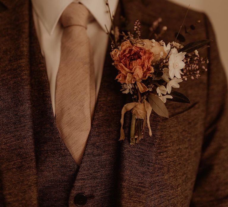 Father of the bride in brown suit, neutral tie and autumnal coloured buttonhole flowers 