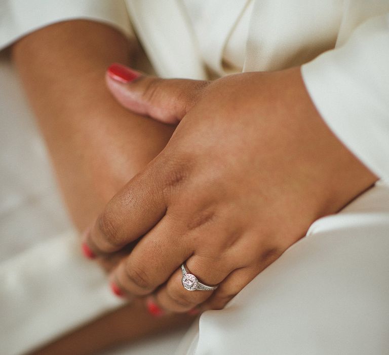 Bride wears round diamond engagement ring with red wedding nails 