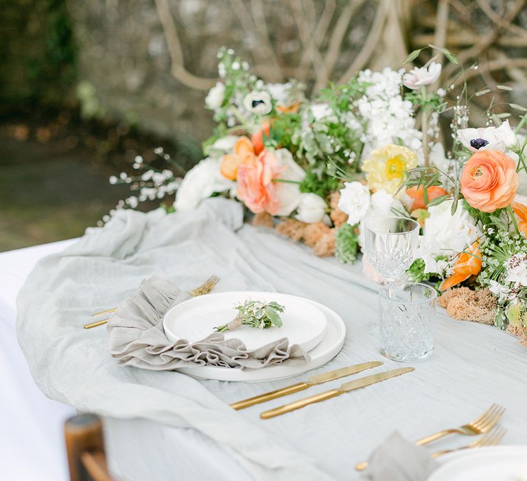 Place setting with white crockery, gold cutlery and fanned out linen napkins 