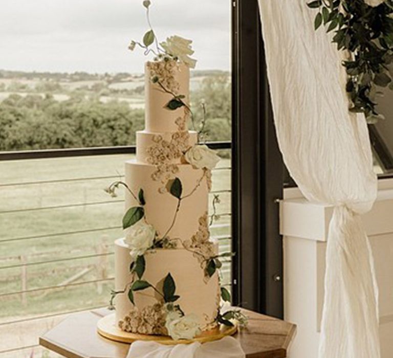 Four tier traditional white wedding cake with lots of greenery and foliage 