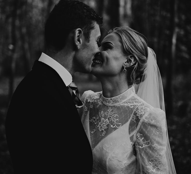 Groom embraces the bride as they smile and lean in for a kiss