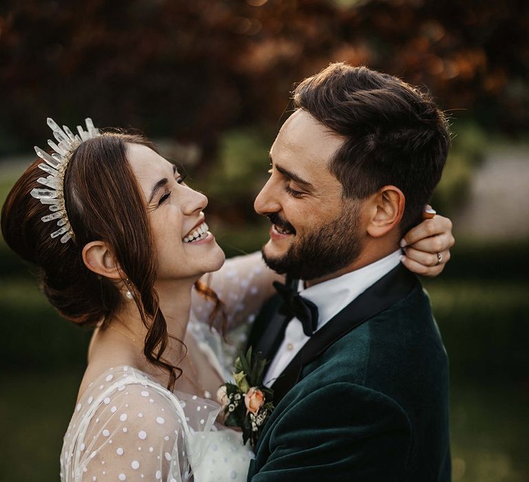 Bride and groom laugh together as they pose for their couple portraits 