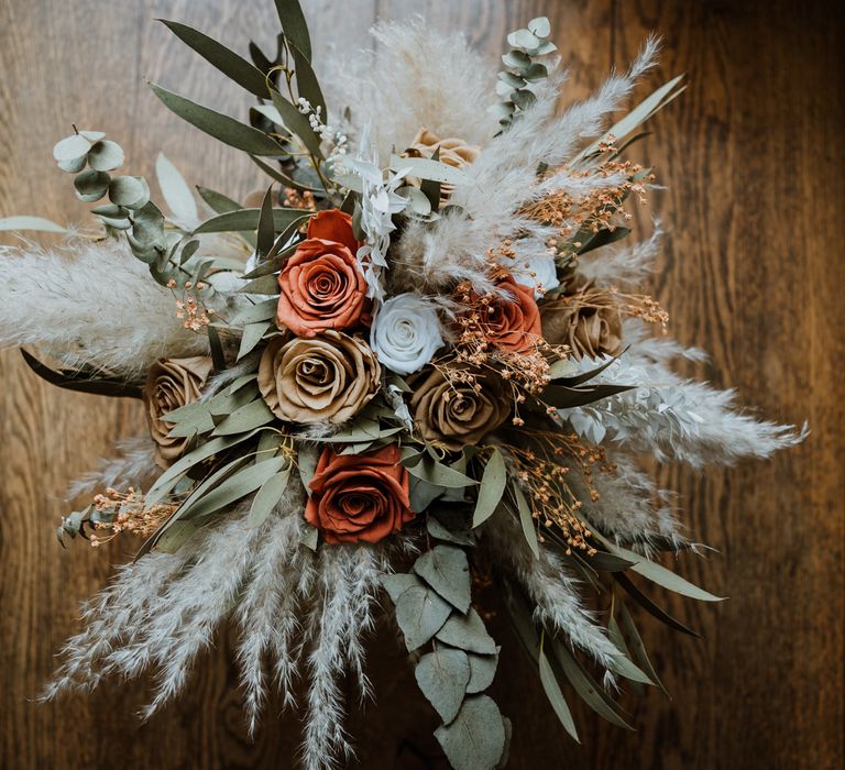 Dried flower wedding bouquet with neutral tones and burnt orange, dark orange, white and brown roses 