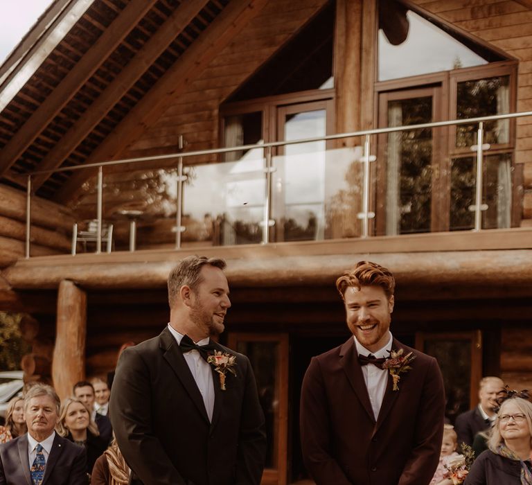 Grooms stand side by side for their autumnal rustic wedding captured by an LGBTQ photographer