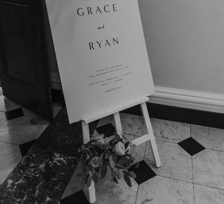 Minimalistic black and white wedding sign with floral bouquet on top at Somerset House